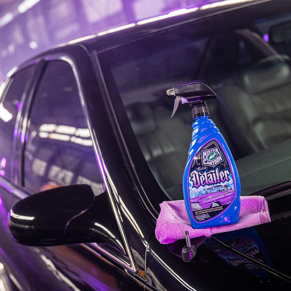 A shiny, dark car with Mister Cartoon Quick Detailer product featuring Turtle Wax logo on a microfiber cloth on the hood.
